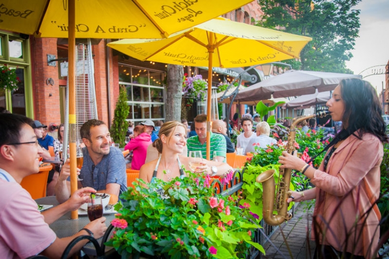 People at restaurant enjoying street performer playing saxaphone