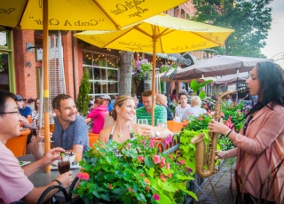 People at restaurant enjoying street performer playing saxaphone