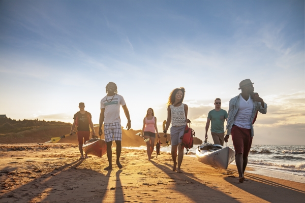 Group on PEI beach carrying canoes at sunset