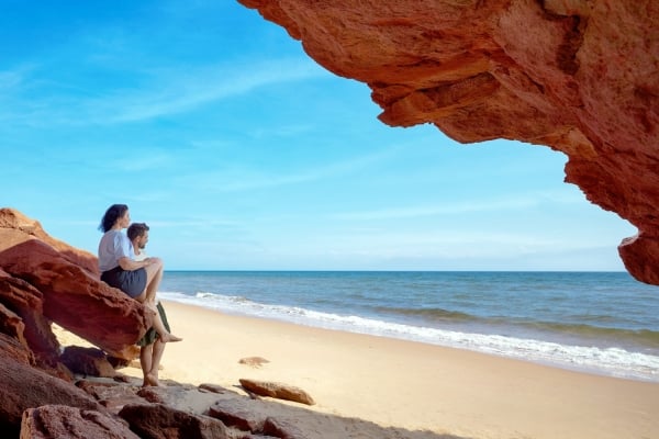 Couple sit on rock watching the waves at Red Point Provincial Park