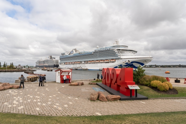 Two cruise ships docked at Port Charlottetown with giant 2024 sign in foreground
