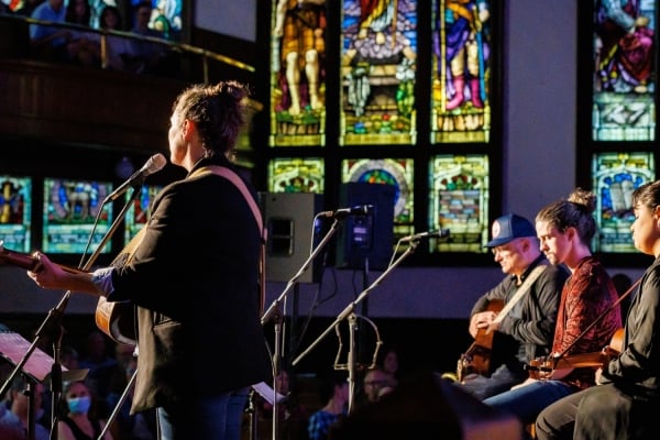 Catherine MacLellan singing with group of musicians in background at a Small Halls Festival venue