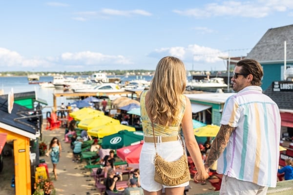 Couple stands overlooking floating dock restaurants at Peake's Quay in summer