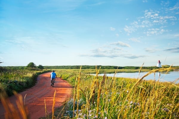 Lone cyclist on red dirt road to St. Peters Lighthouse in summer
