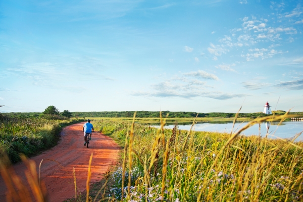 Lone cyclist on red dirt road to St. Peters Lighthouse in summer