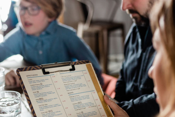 Close-up view of female holding menu with child and male at same table