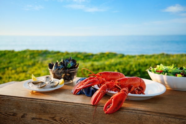 Plated PEI seafood and salad on a table with beach in background