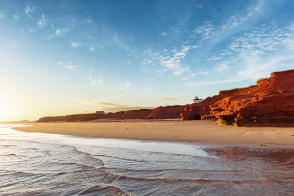 Wide view of beach at Thunder Cove at sunset with red cliffs and cottages in the distance