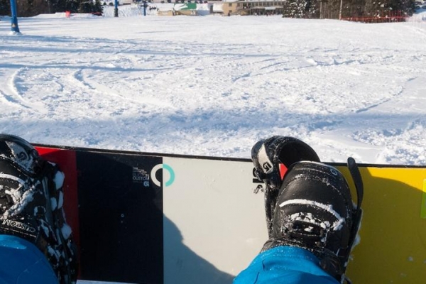 Snowboarder sitting at top of hill looking down