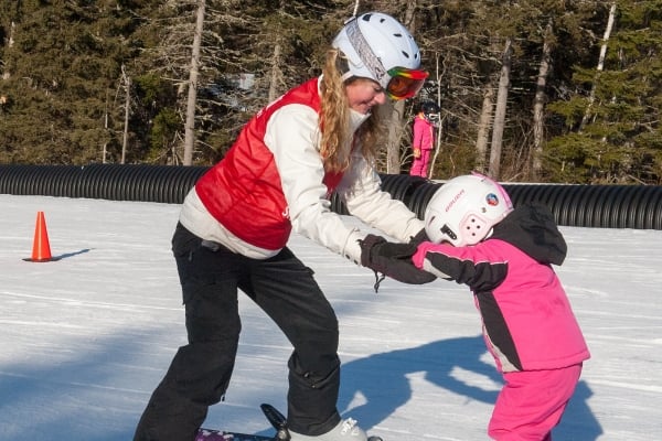 Instructor assisting young skier on hill