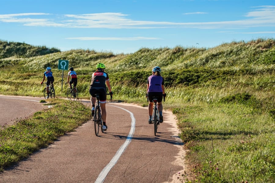 Group of bikers cycling along bike path at PEI National Park - Brackley Beach