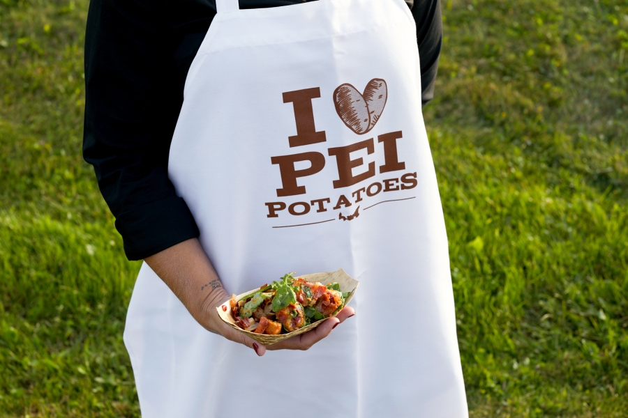 Person in "I Love PEI Potatoes" apron holds tasty looking potato dish