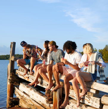 A group of friends sitting on a wooden dock by the water