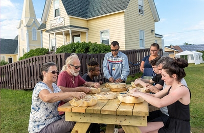 Group of people sitting at picnic table learning to make drums on Lennox Island
