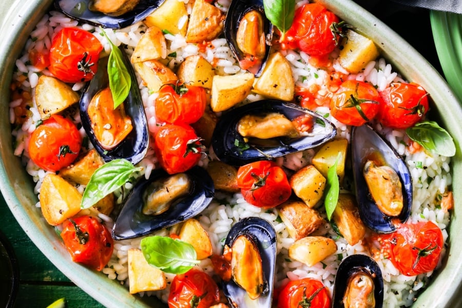 One dish meal of rice, steamed mussels, cherry tomatoes and potatoes in a cream sauce