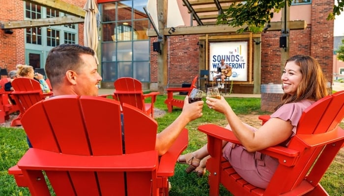 Couple sit in lawn chairs and make a toast while listening to live music in summer