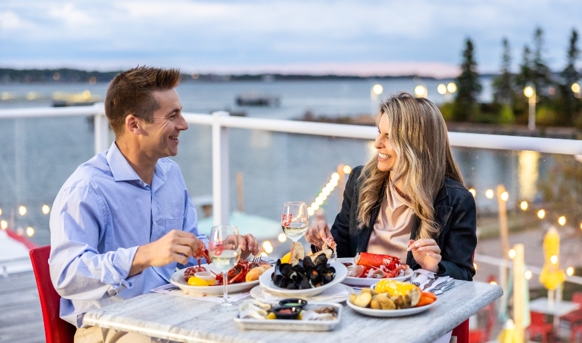 Couple dining on lobster supper on patio overlooking Charlottetown Harbour in summer