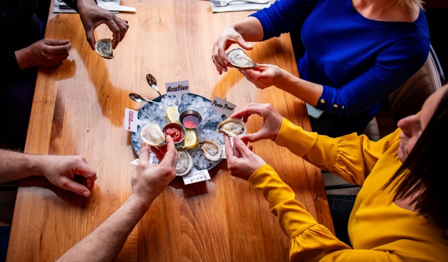 Overhead view of group of four enjoying oysters on half shell in PEI restaurant