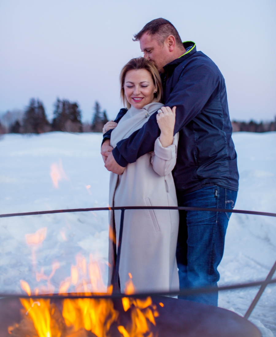 Couple embrace near outdoor fire pit in winter