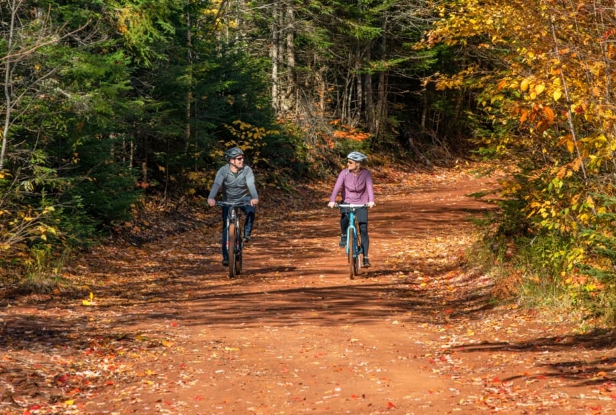 Two cyclists in street clothes and wearing helmets on scenic heritage road in Bonshaw, PEI