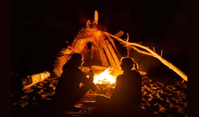 Two people enjoy fire on beach