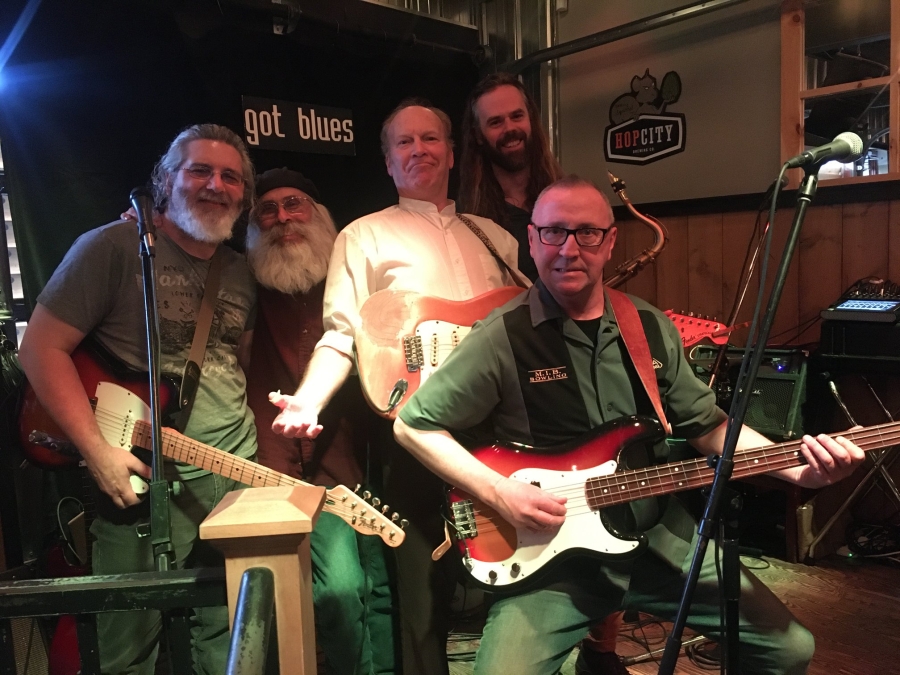 Blues Matinee five gentlemen grouped together , two with guitars on stage at the got blues matinee.