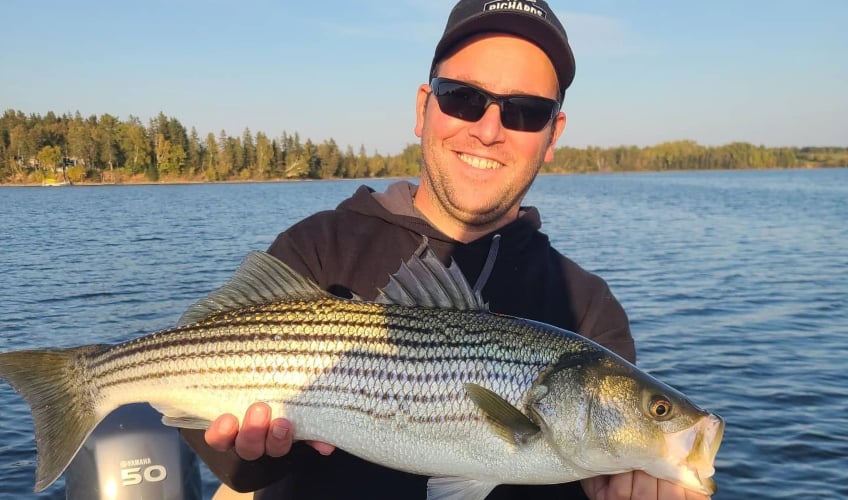 Richard's Bait & Tackle crew member holds large striped bass