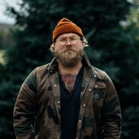 Portrait image of Al Douglas standing in front of an evergreen