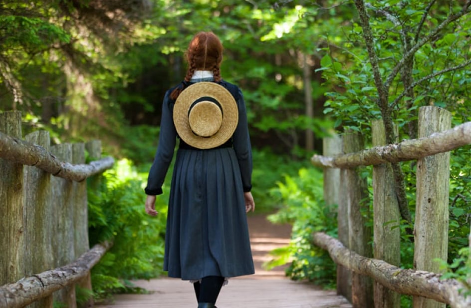 Rear view of Anne of Green Gables walking down a wooden bridge