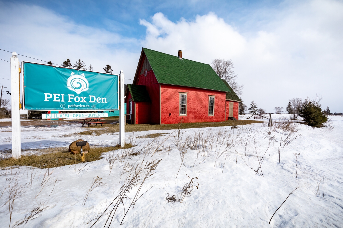 PEI Fox Den, PEI PEI Fox Den sign with red schoolhouse in background in winter