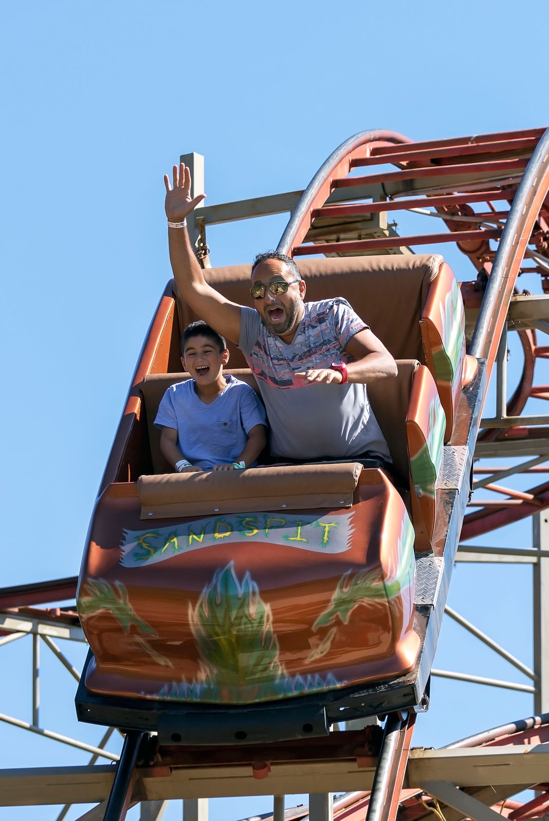 Adult male and child enjoy roller coaster at Sandspit Amusement Park
