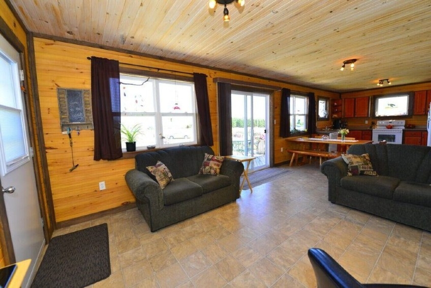 Living room area surrounded by wood walls and ceiling with rustic decor