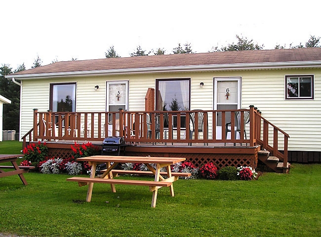 Cottage with yellow siding, front deck and outdoor picnic table 