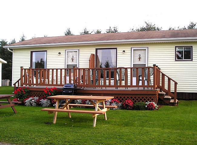 Cottage with yellow siding, front deck and outdoor picnic table