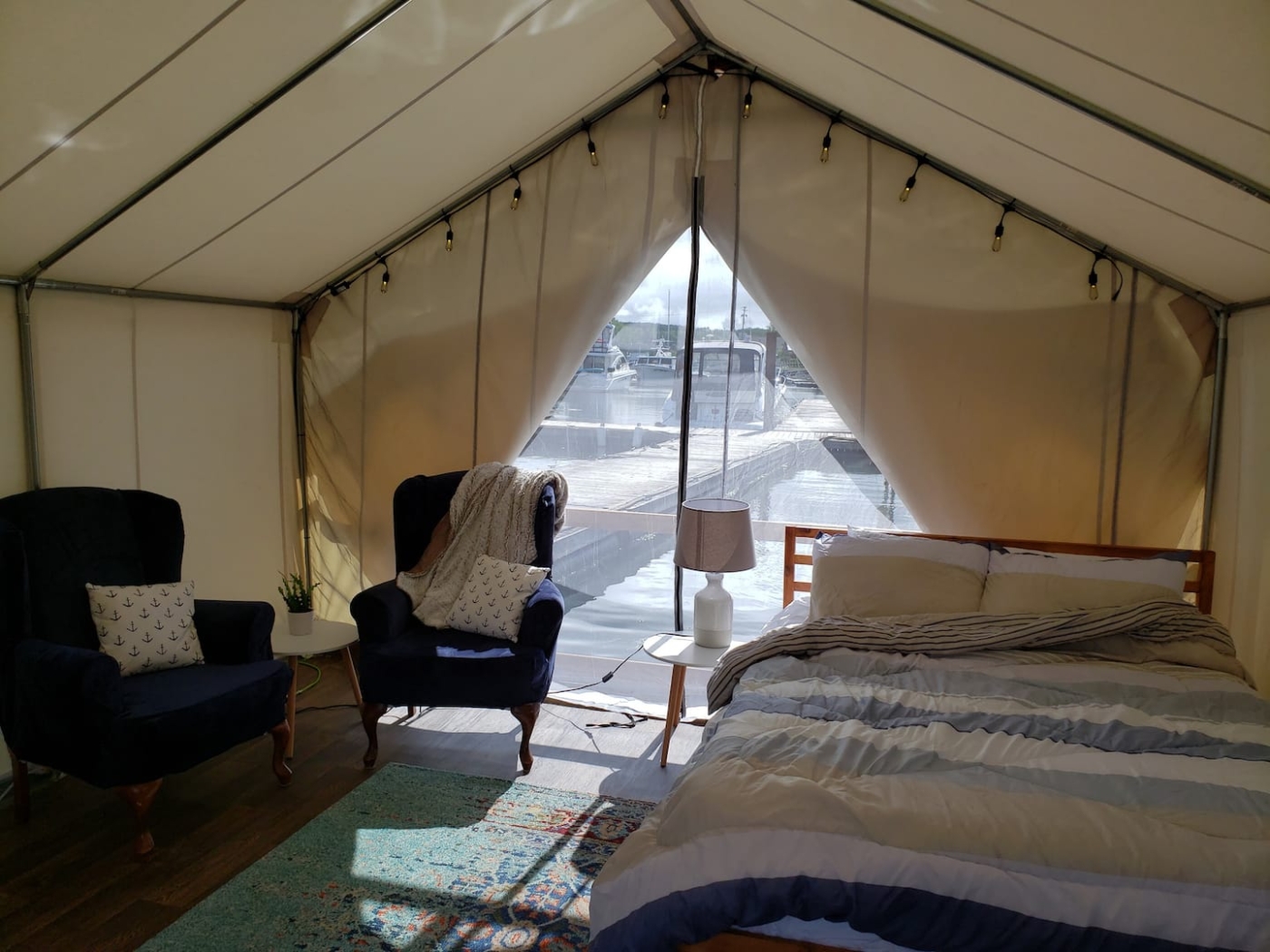 Inside view of bed and two wing back chairs looking out onto the marina