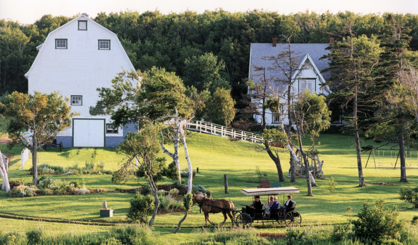 Grounds of Anne of Green Gables Museum in summer with horse and carriage in foreground