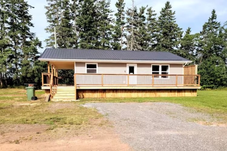 Baird's Country Guest House outside front view of beige cottage and trees behind it