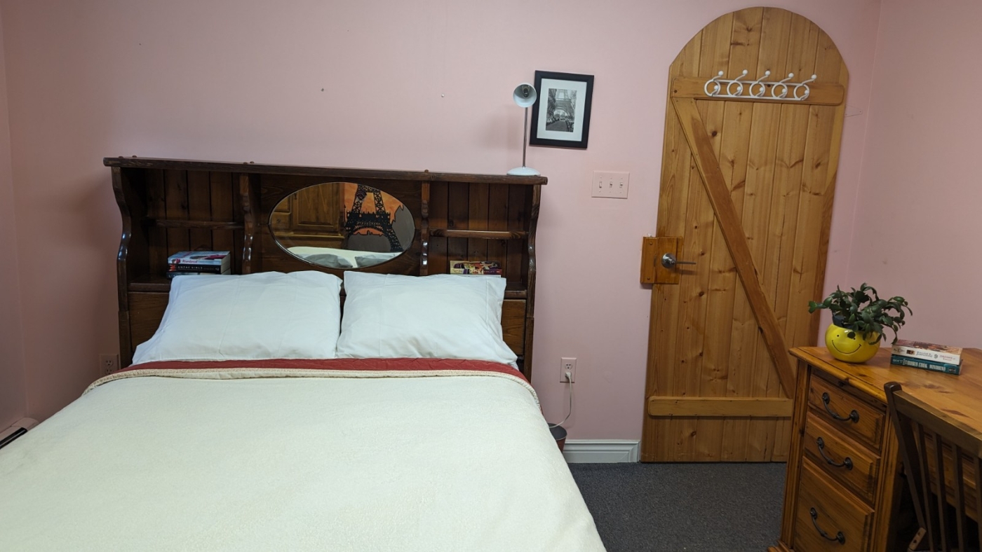 Double bed with cream bedspread and blush rose walls with pine door
