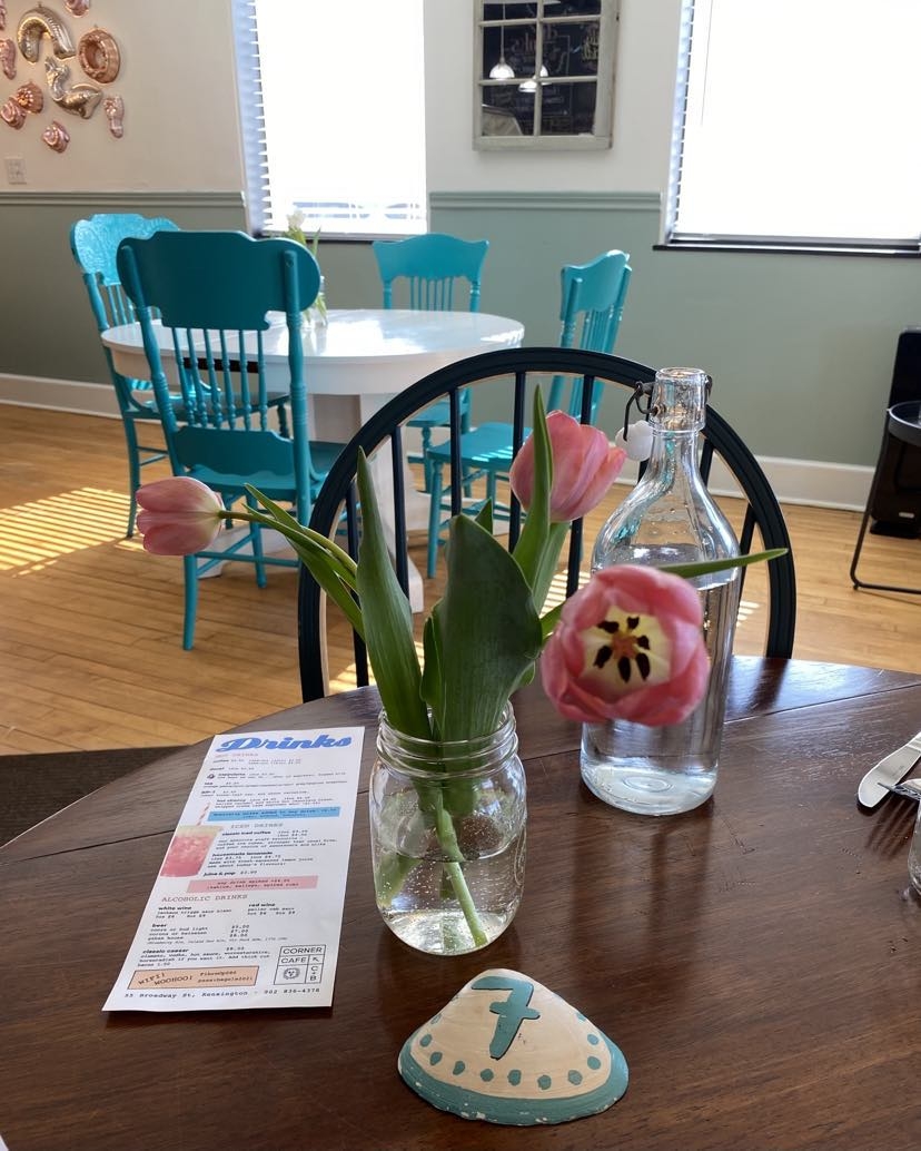 Interior view of table with vase of tulips, shell table marker and menu at C&B Corner Cafe, Kensington