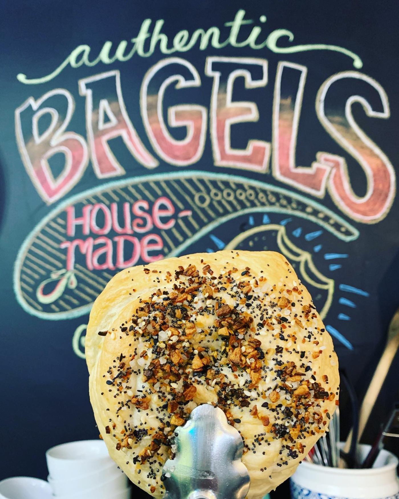 Bagel in foreground with text "authentic housemade bagels" in background