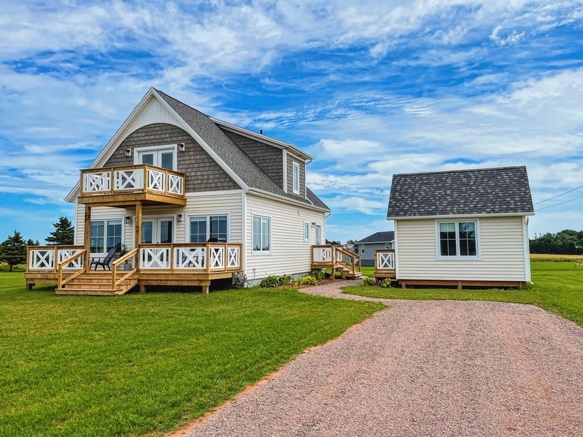 Cape House outside photo, looking from the driveway at a beige cottage with two decks and s