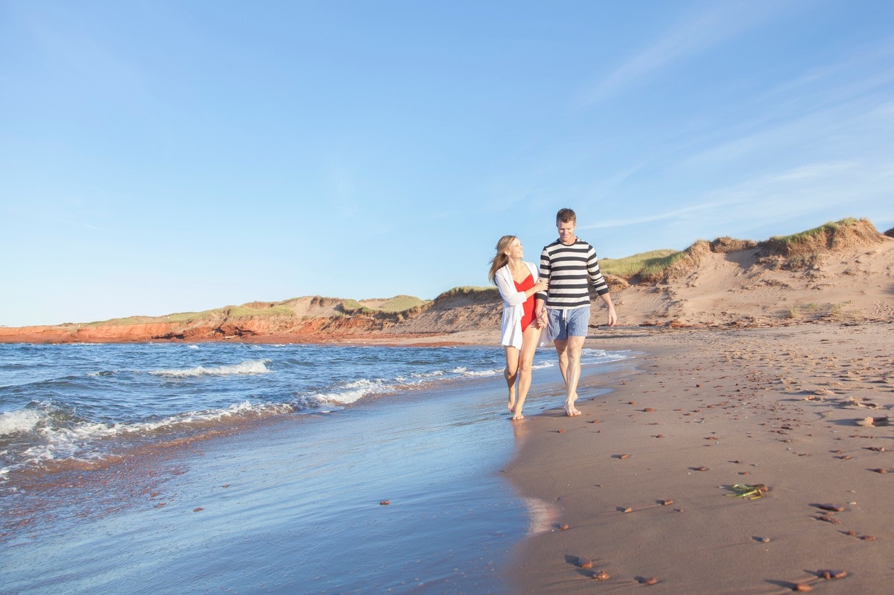 Male and female couple walking along Cavendish Beach
