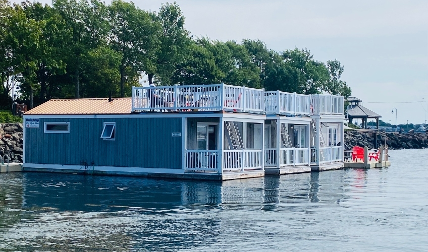 Three grey floating cottages on the water at Peake's Quay with rooftop decks