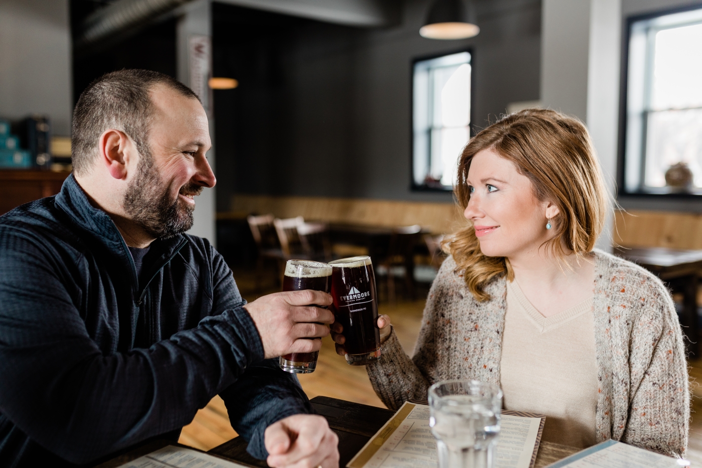 Couple raise beer glasses for a toast, Evermoore Brewing Co