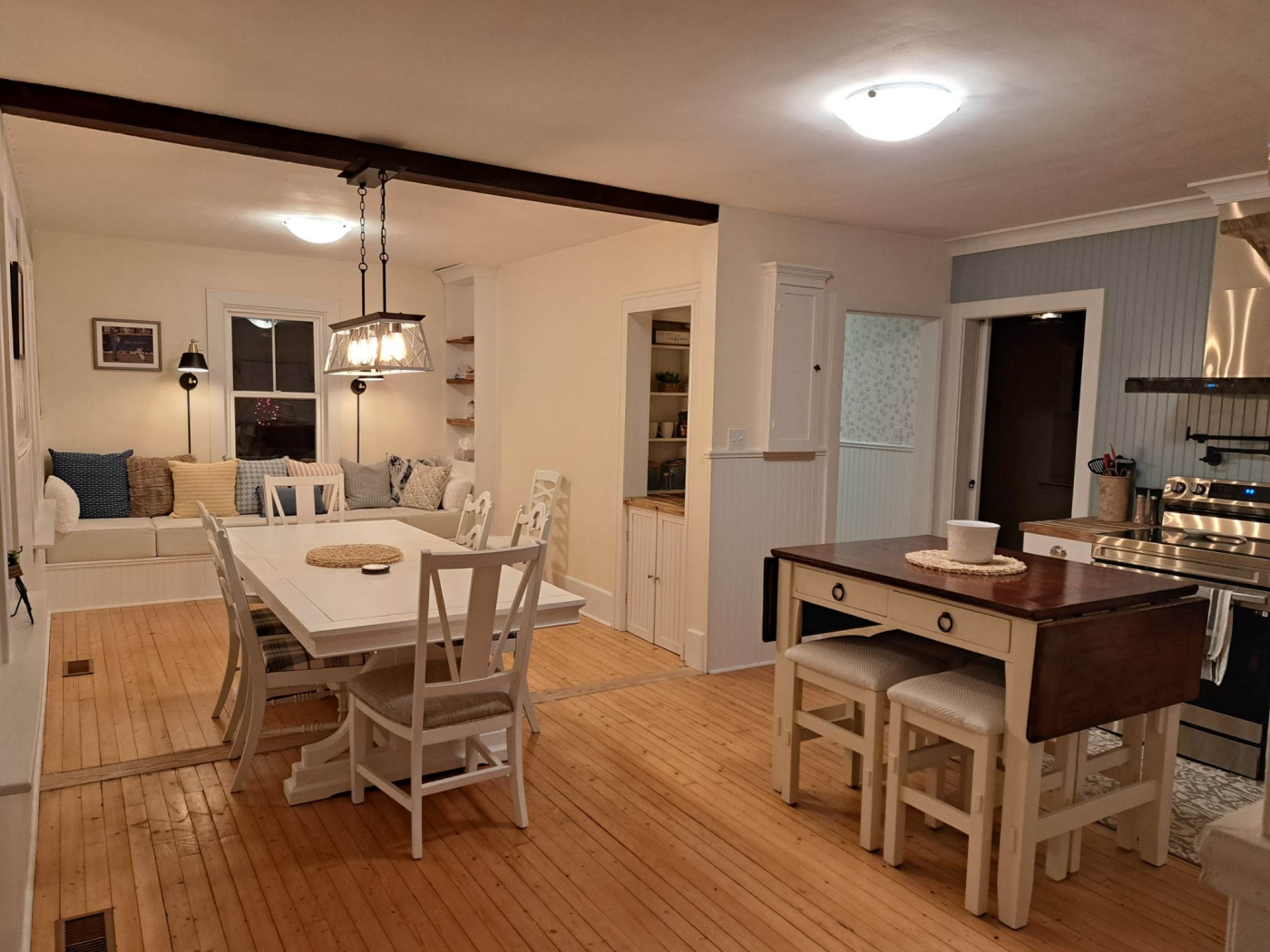 Image of kitchen and dining area with white table and chairs and island also has seating