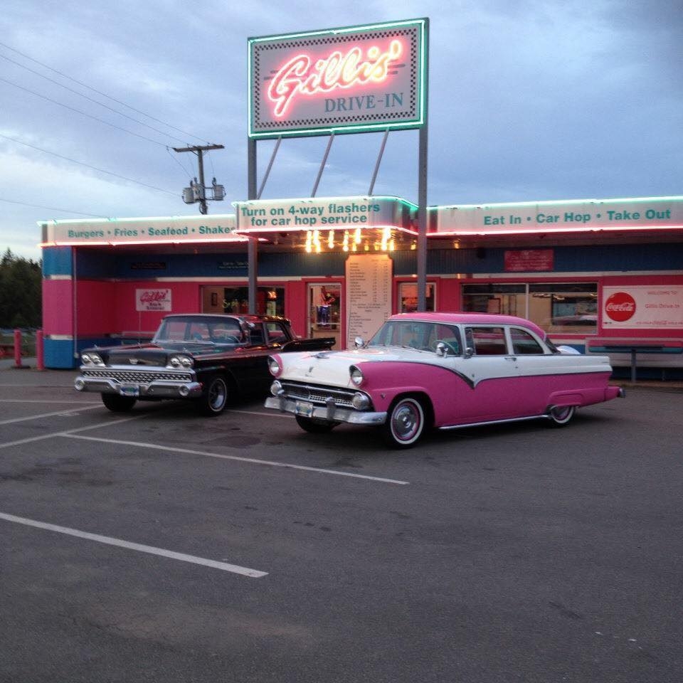 Exterior view of Gillis' Drive In with two classic cars sitting out front