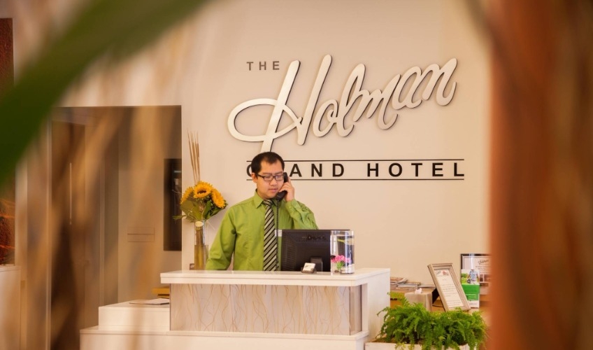 Staff member on phone at front desk of the Holman Grand Hotel