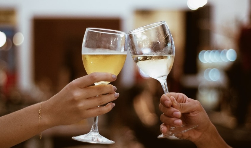 Stock image of two persons tapping glasses of wine