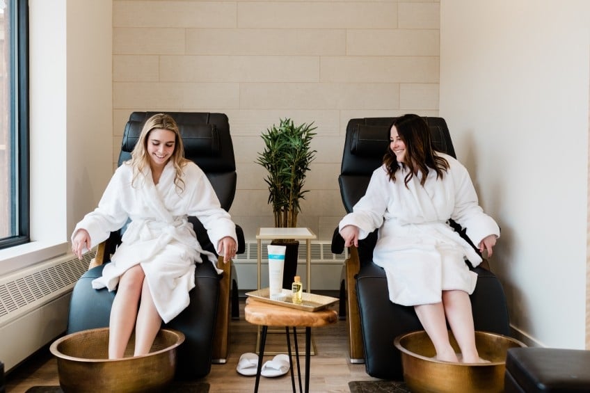 A couple of women enjoying a pedicure, dressed in white robes