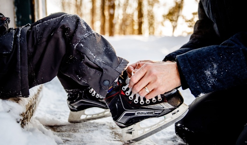 Adult tying a child's skates outdoors